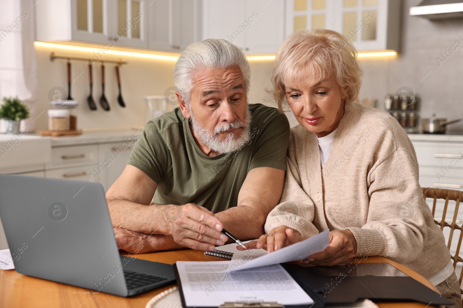 Photo of Pension savings. Senior couple planning budget at wooden table indoors