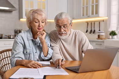 Photo of Pension savings. Senior couple planning budget at wooden table indoors