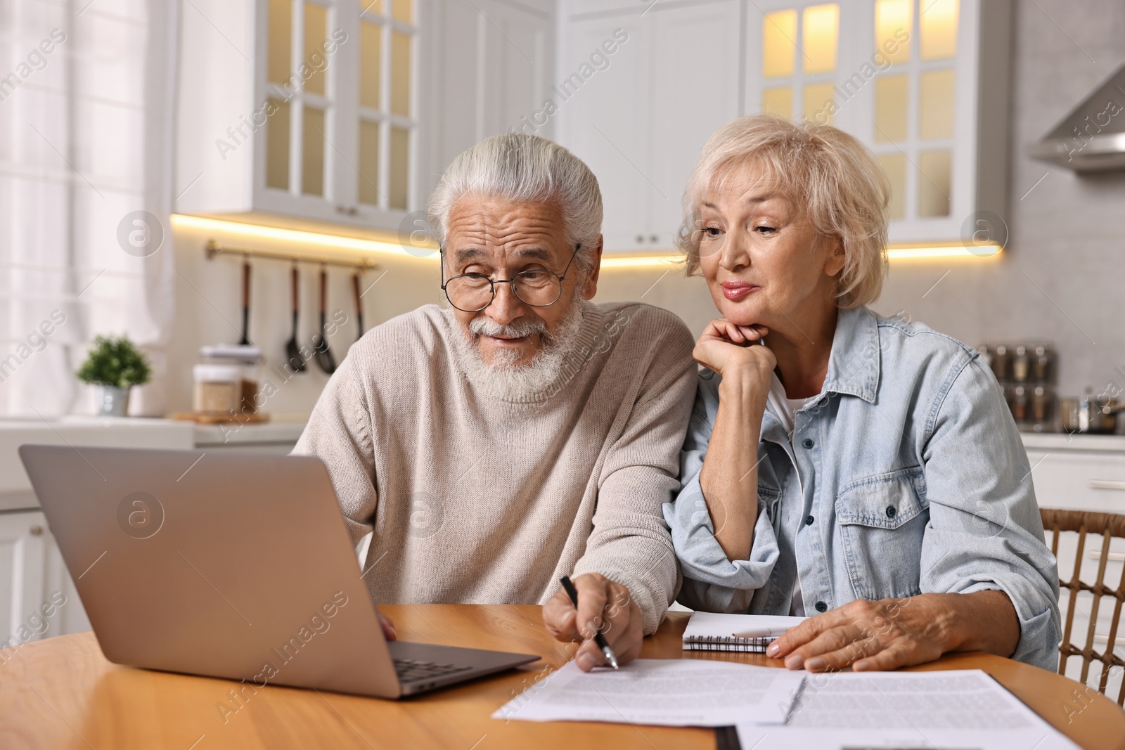 Photo of Pension savings. Senior couple planning budget at wooden table indoors