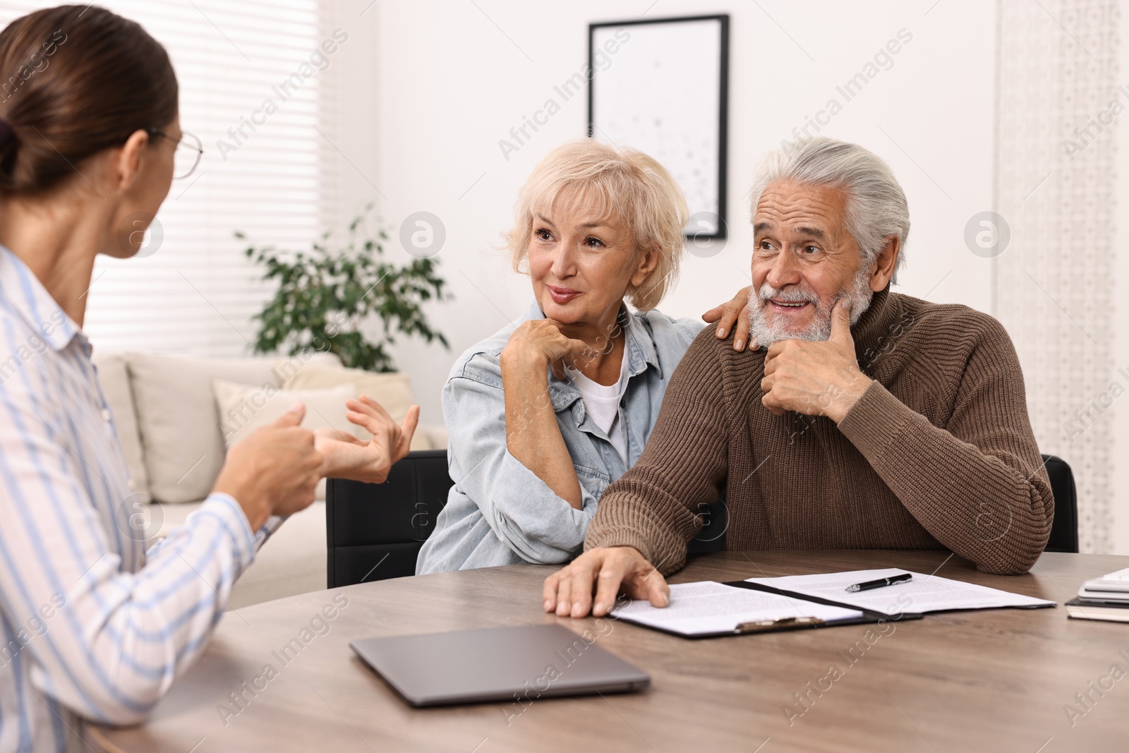 Photo of Pension plan. Senior couple consulting with insurance agent at wooden table indoors