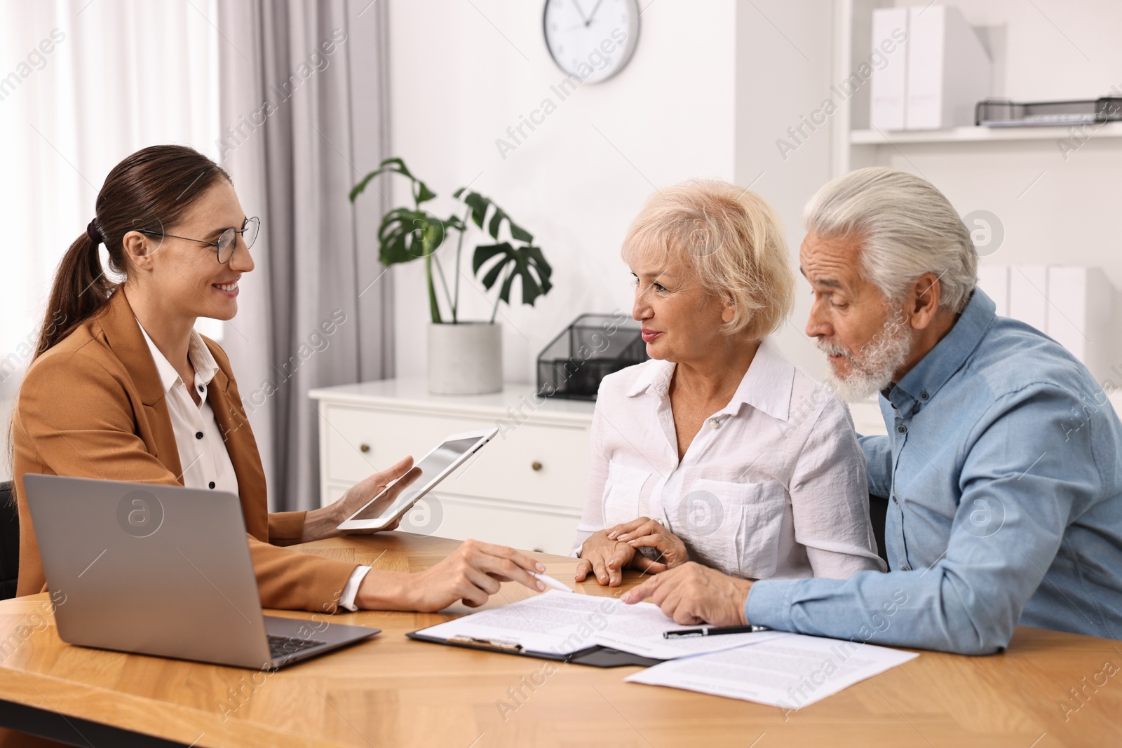 Photo of Pension plan. Senior couple consulting with insurance agent at wooden table indoors