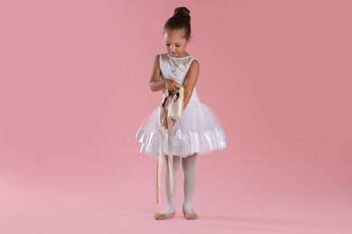 Photo of Little ballerina with pointe shoes on pink background