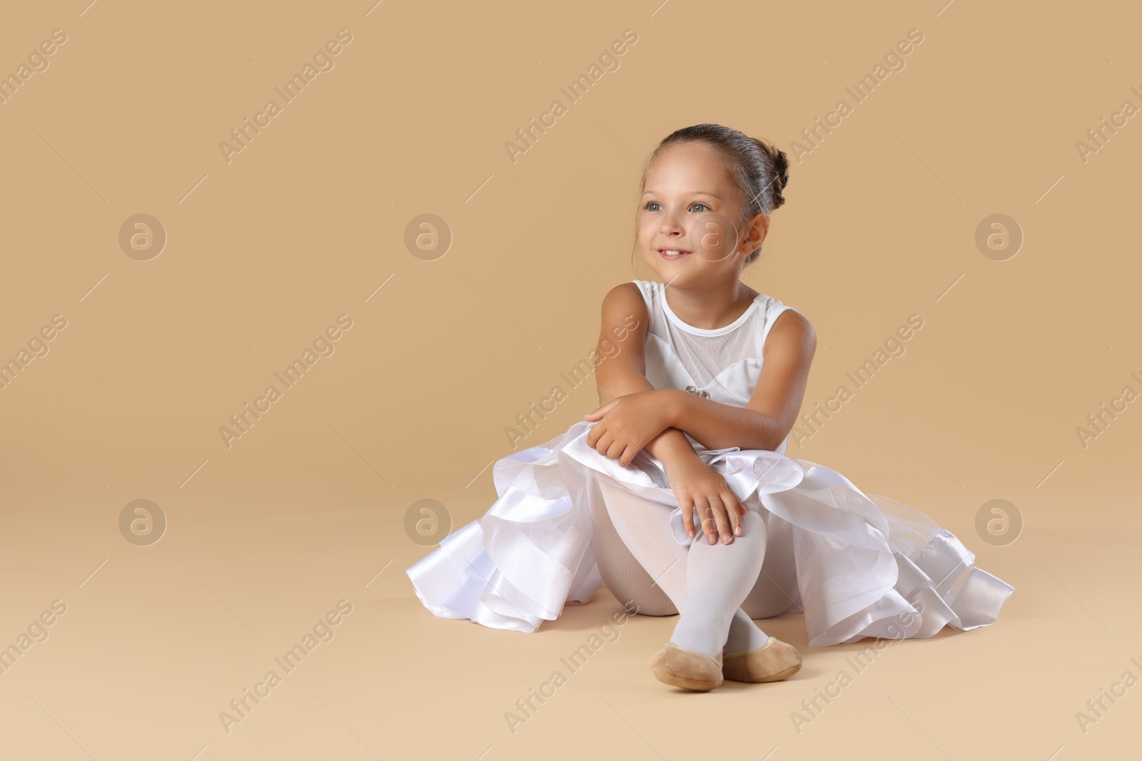 Photo of Portrait of little ballerina on beige background, space for text