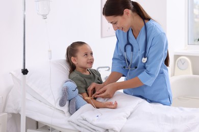 Photo of Doctor examining little girl on bed at hospital