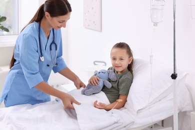 Photo of Doctor examining little girl on bed at hospital