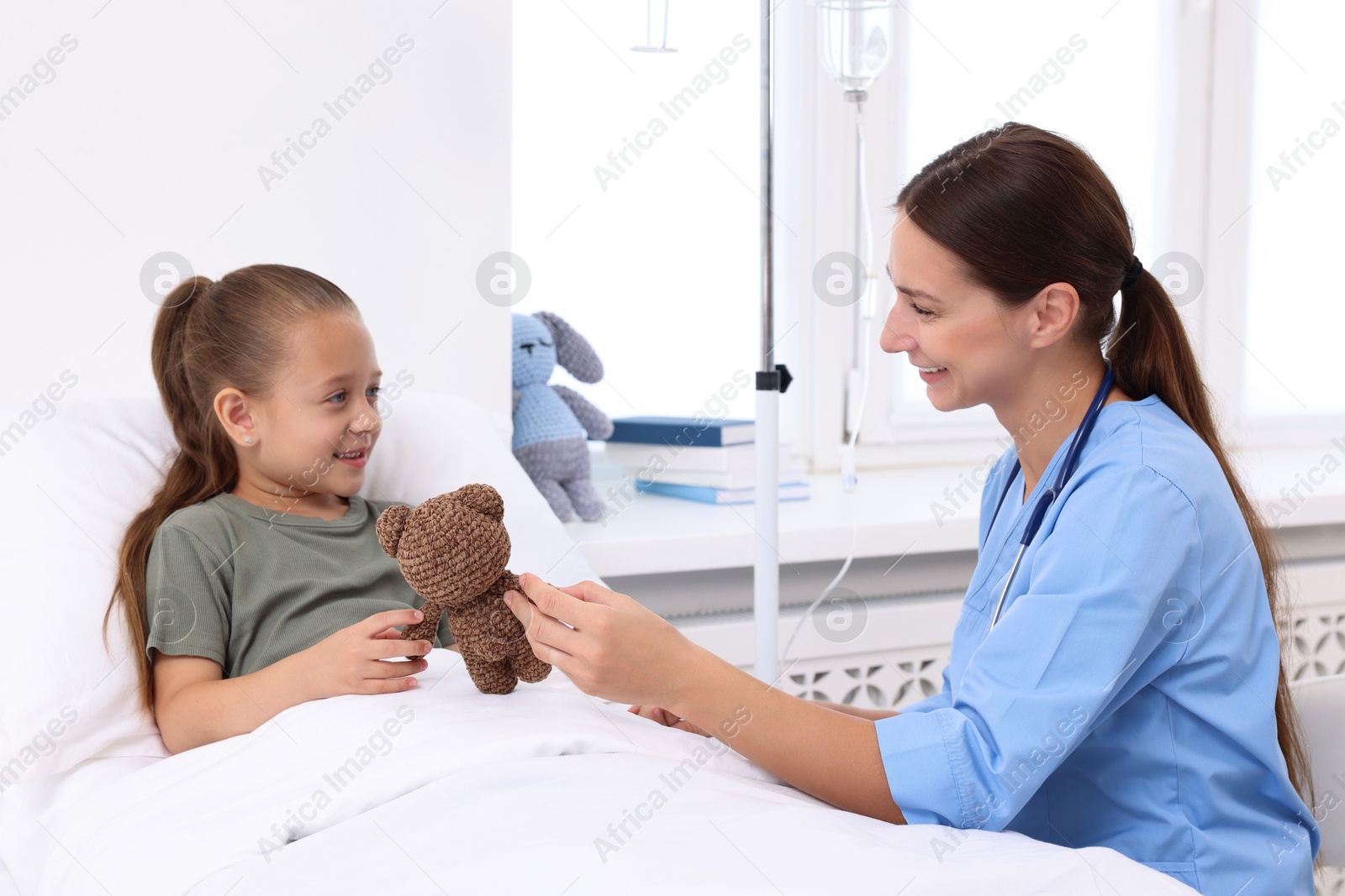 Photo of Doctor examining little girl on bed at hospital