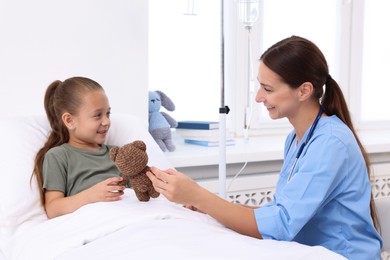 Photo of Doctor examining little girl on bed at hospital