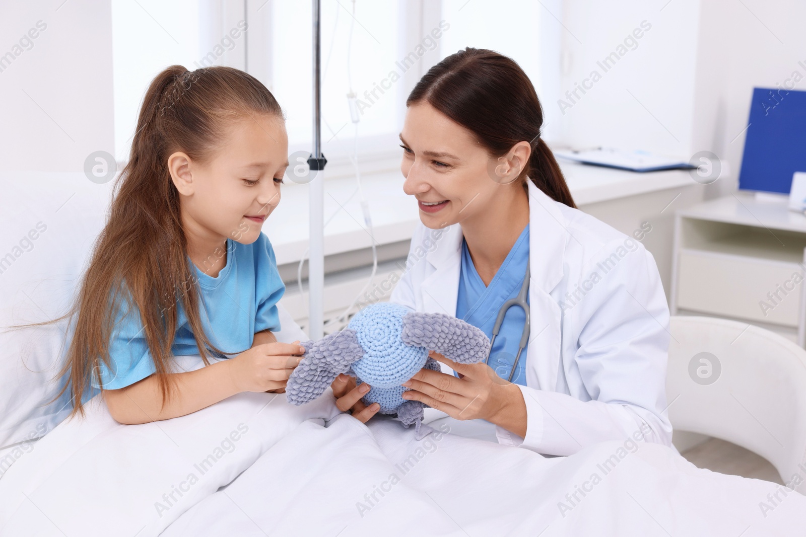 Photo of Doctor examining little girl on bed at hospital