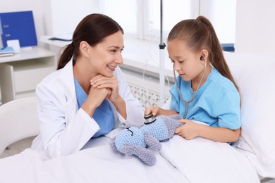 Doctor examining little girl on bed at hospital