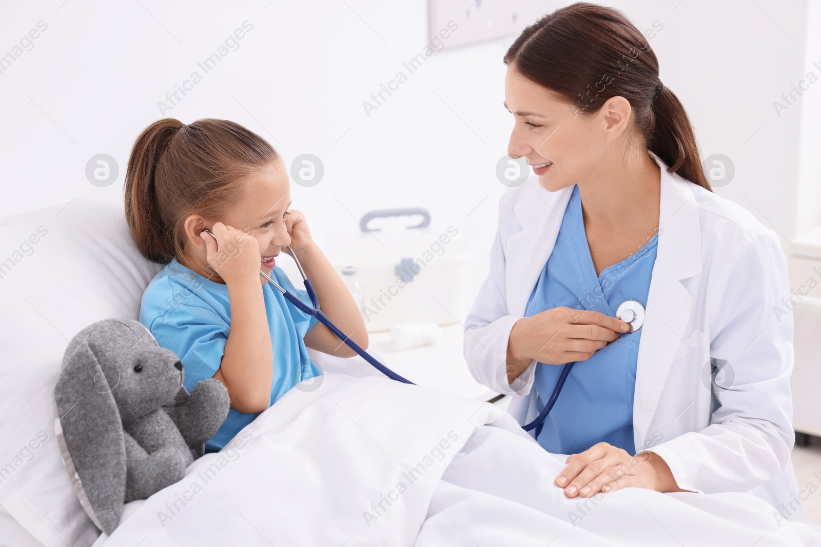 Photo of Doctor examining little girl on bed at hospital