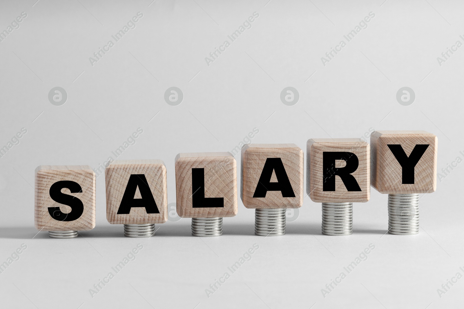 Photo of Word Salary made of wooden cubes and coins on light grey background, space for text