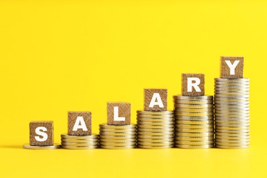 Photo of Blank wooden cubes and stacked coins on yellow background