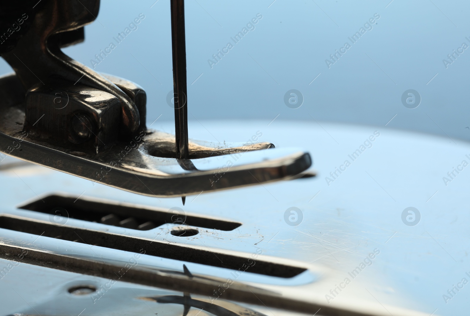 Photo of Sewing machine on light blue background, macro view. Space for text