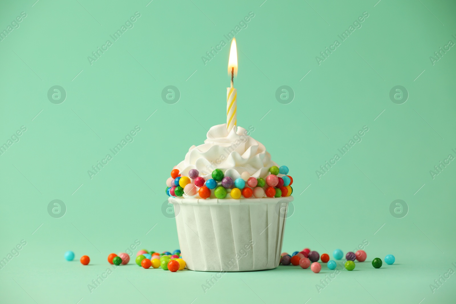 Photo of Birthday cupcake with burning candle on turquoise background