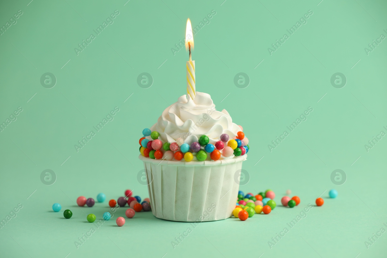 Photo of Birthday cupcake with burning candle on turquoise background