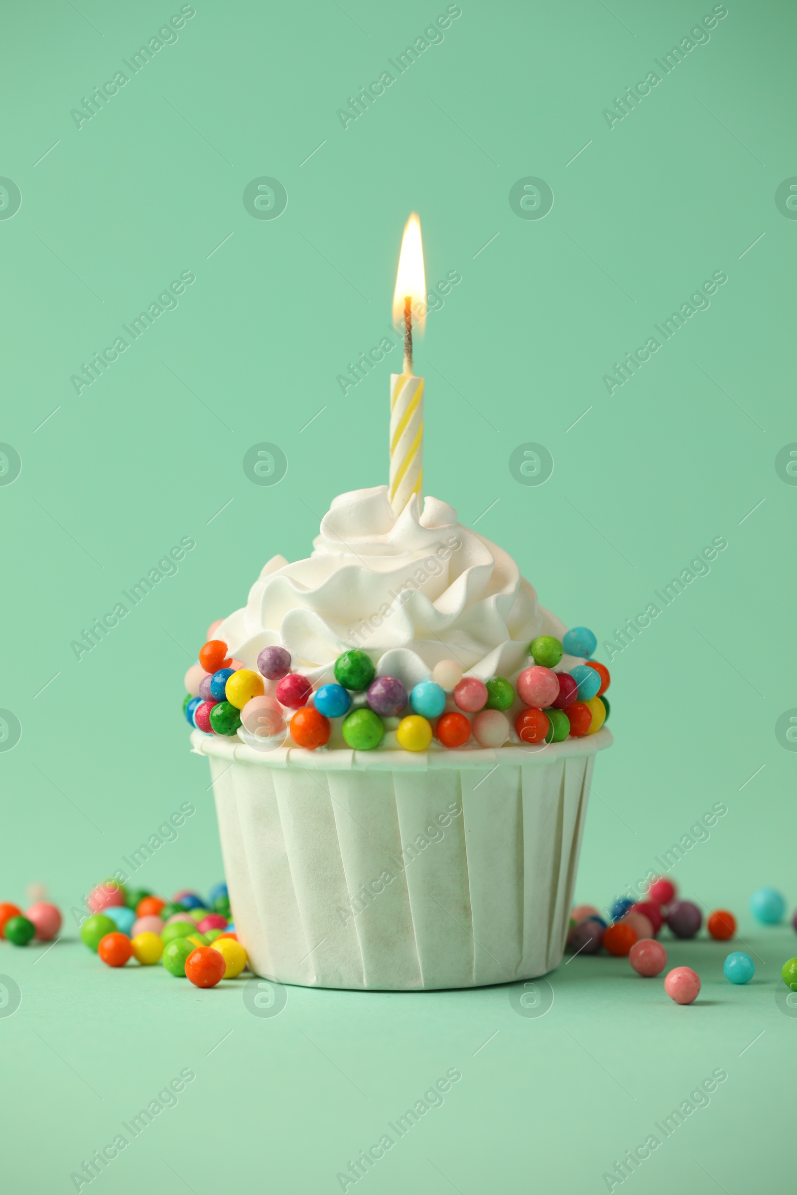 Photo of Birthday cupcake with burning candle on turquoise background