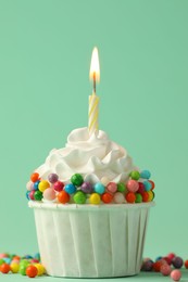 Photo of Birthday cupcake with burning candle on turquoise background