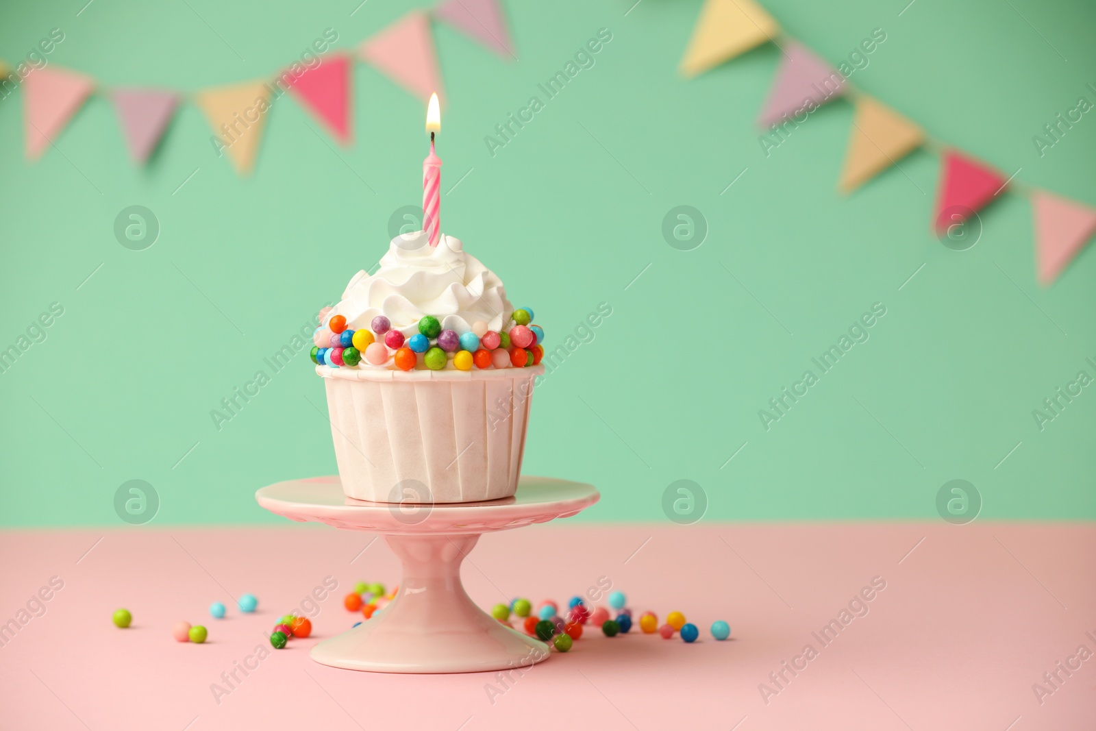 Photo of Birthday cupcake with burning candle on pink table. Space for text