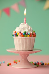 Photo of Birthday cupcake with burning candle on pink table