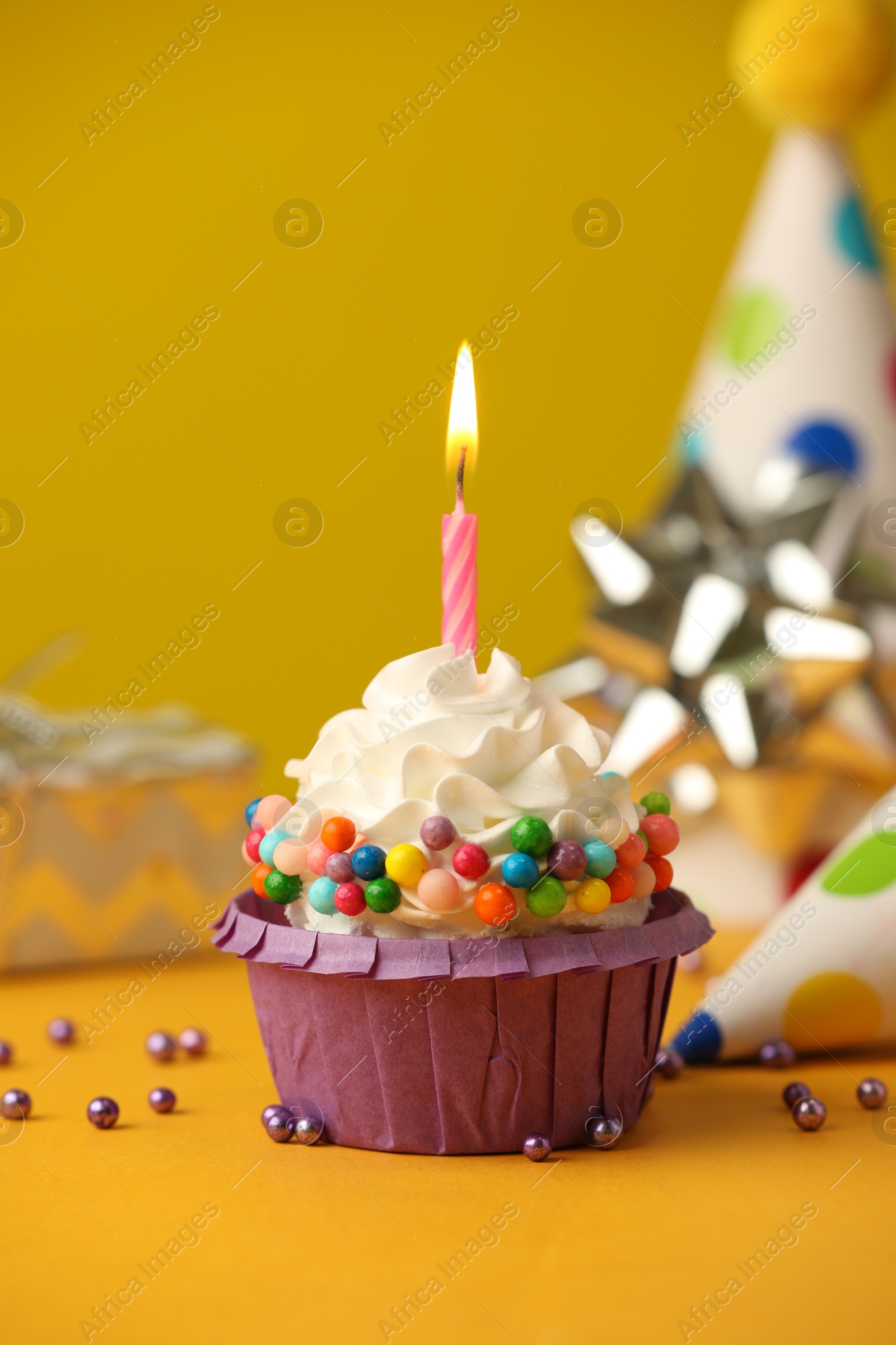 Photo of Birthday cupcake with burning candle on yellow table