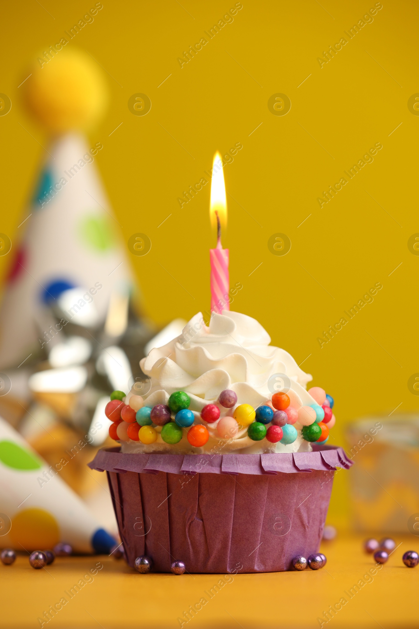 Photo of Birthday cupcake with burning candle on yellow table