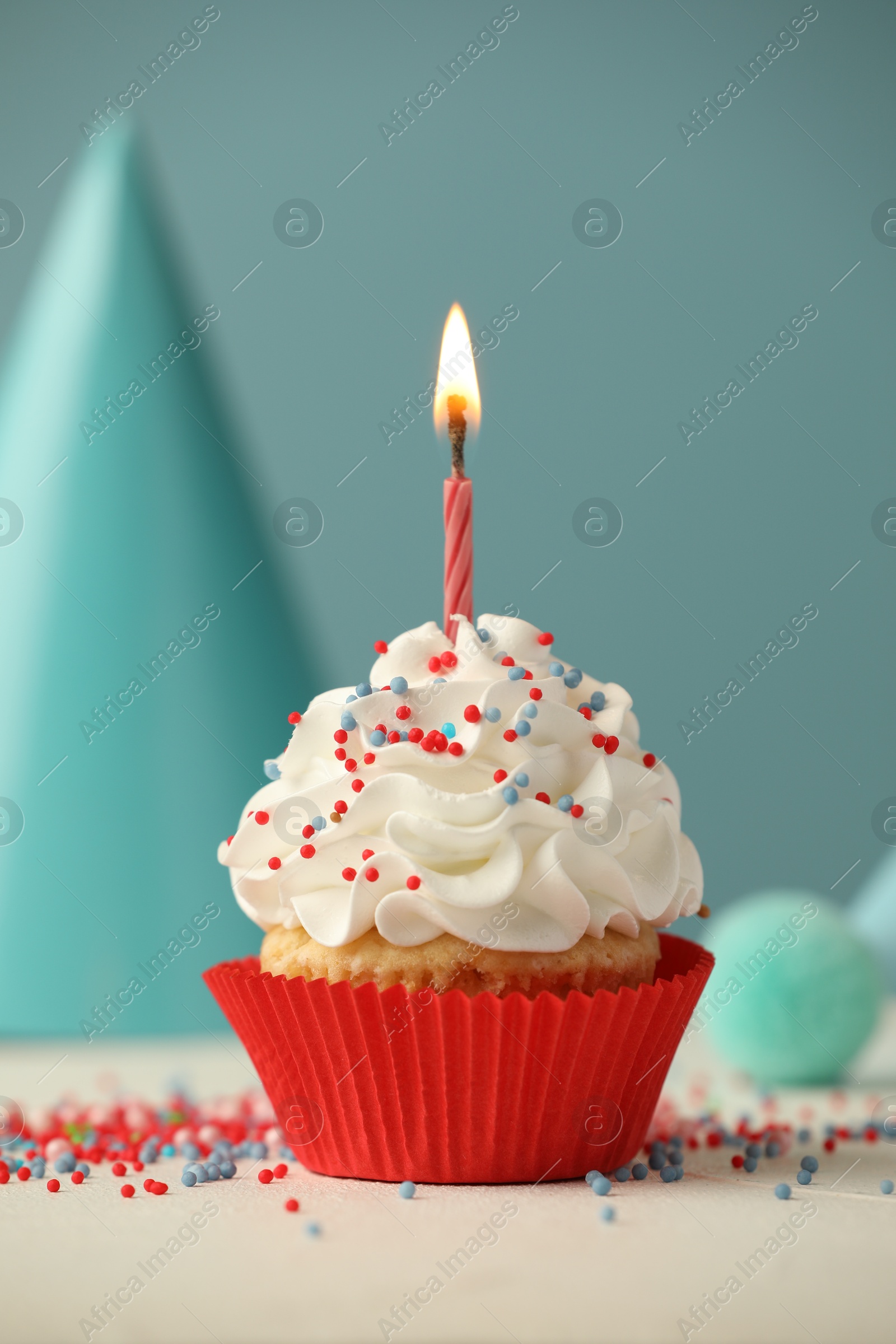 Photo of Birthday cupcake with burning candle and party cone on white table