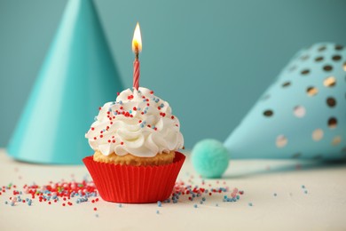 Photo of Birthday cupcake with burning candle and party cones on white table