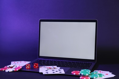 Online poker. Playing cards, chips, dice and laptop on dark table