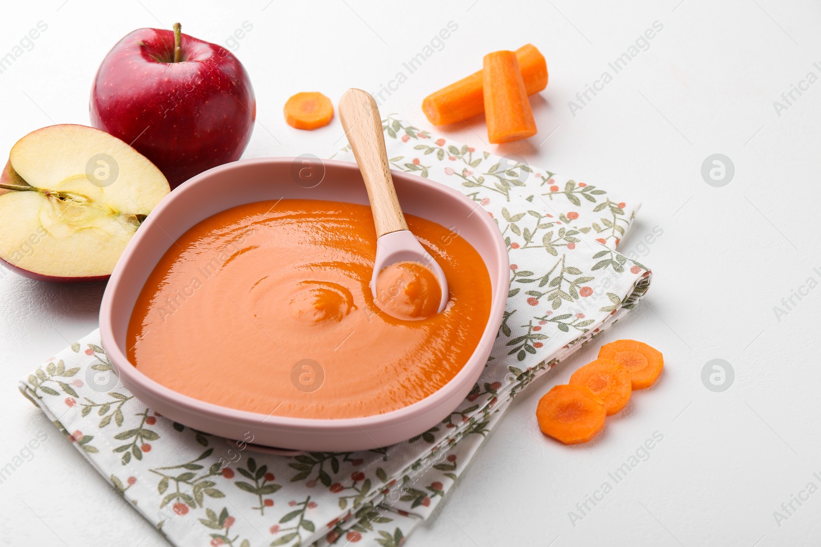 Photo of Delicious baby food in bowl and ingredients on white table