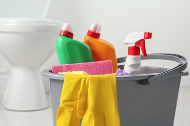 Photo of Bucket with different toilet cleaners in bathroom, closeup