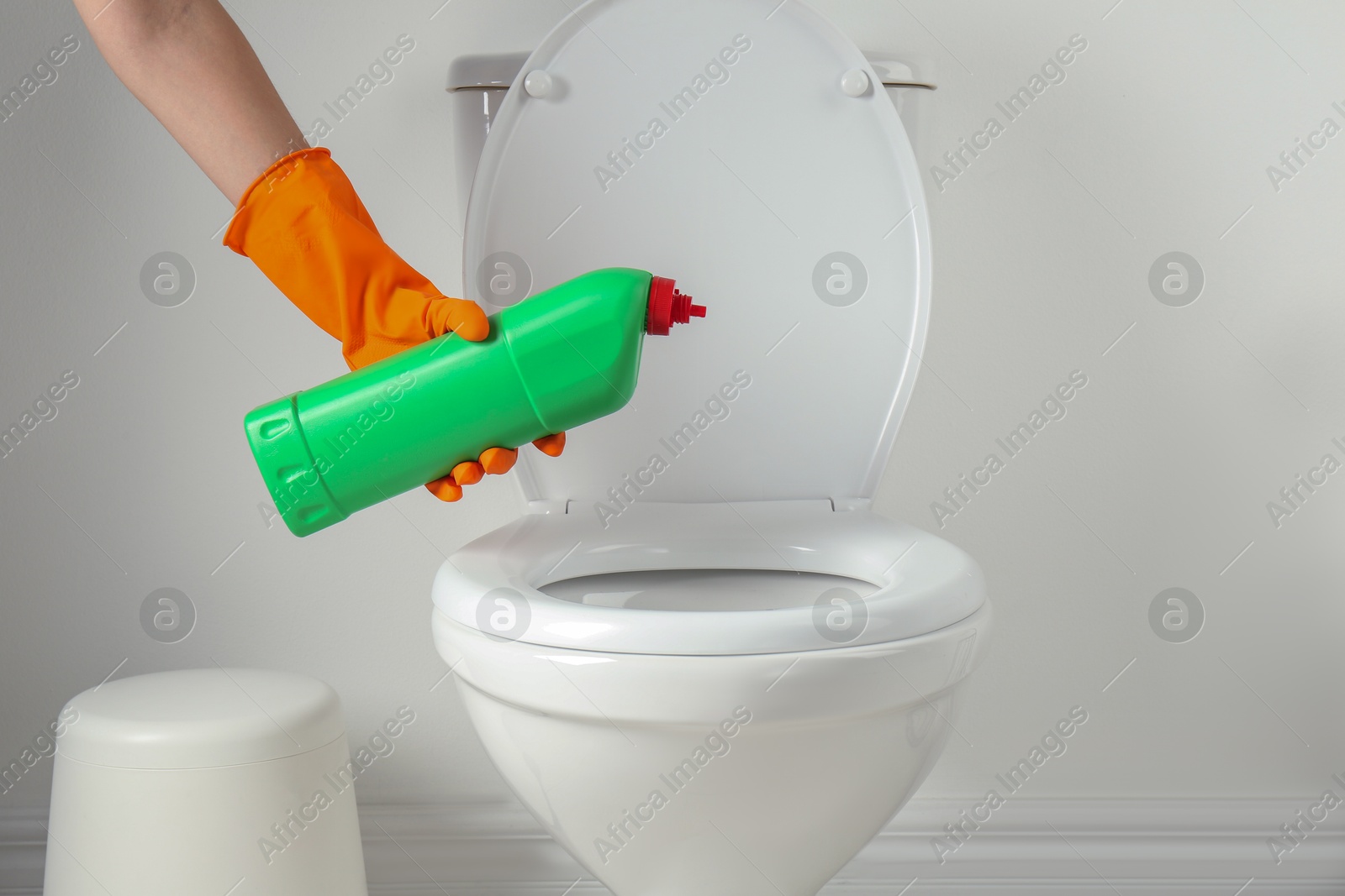 Photo of Woman with detergent cleaning toilet seat in bathroom, closeup