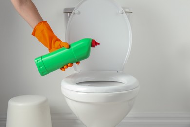 Photo of Woman with detergent cleaning toilet seat in bathroom, closeup