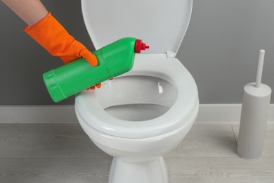 Photo of Woman cleaning toilet with detergent in bathroom, closeup