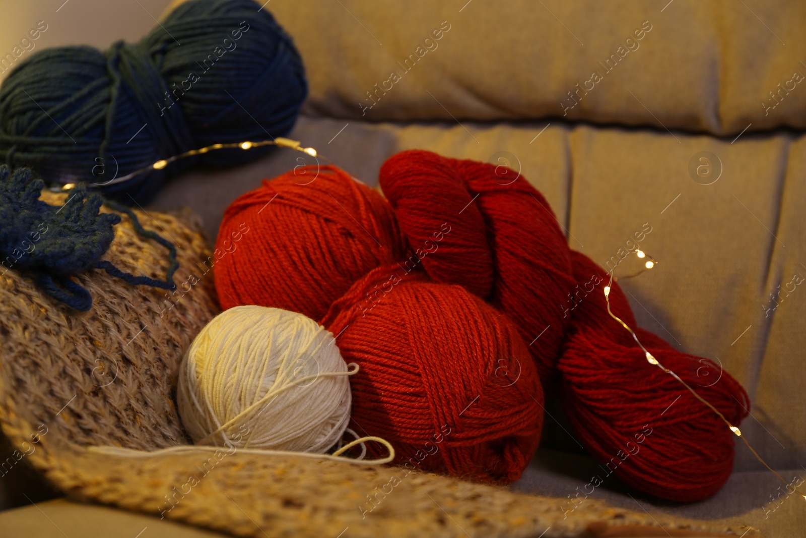 Photo of Knitting material. Skeins of soft yarn on sofa indoors