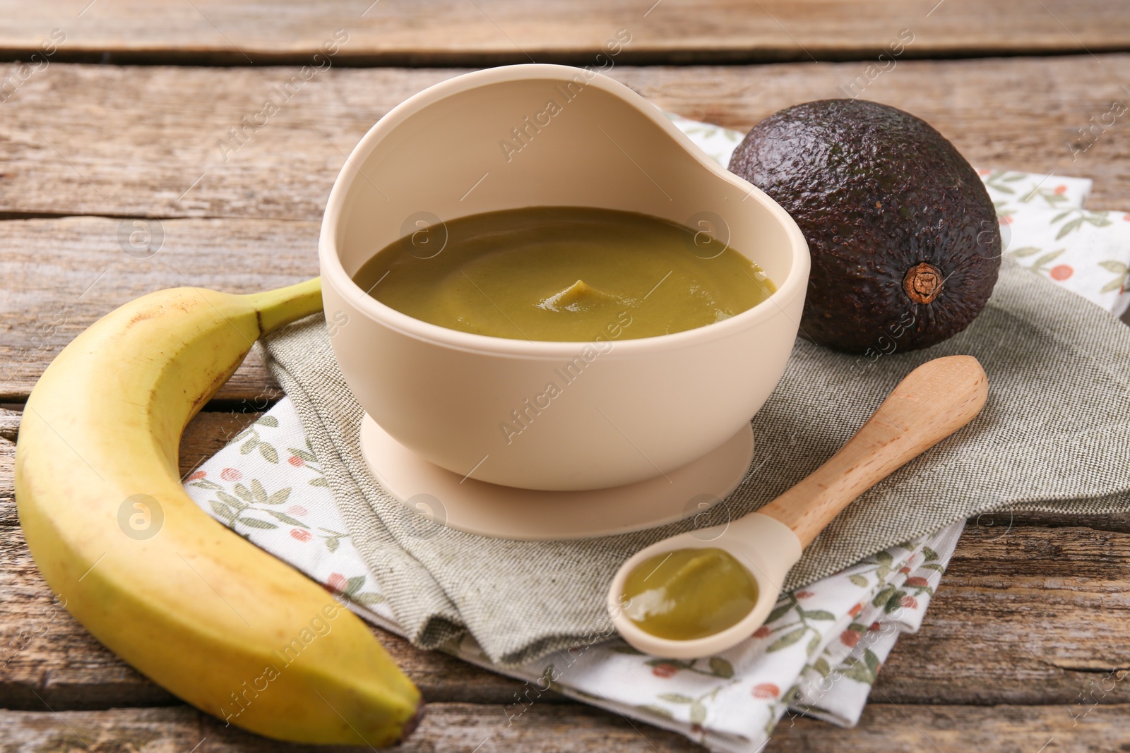 Photo of Delicious baby food in bowl with spoon and fresh ingredients on wooden table