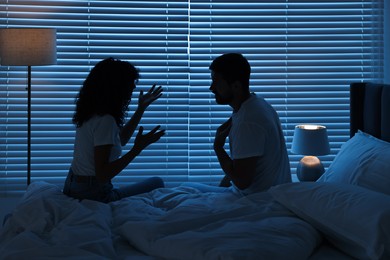 Photo of Emotional couple arguing in bedroom at night. Relationship problems