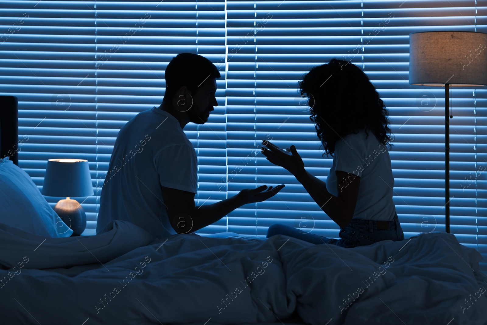 Photo of Emotional couple arguing in bedroom at night. Relationship problems