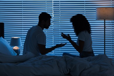 Emotional couple arguing in bedroom at night. Relationship problems