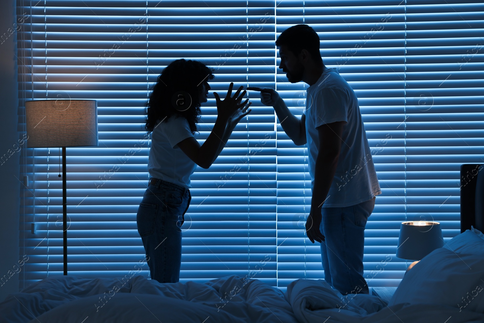 Photo of Emotional couple arguing in bedroom at night. Relationship problems