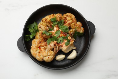 Photo of Tasty cauliflower steak in frying pan on white marble table, top view