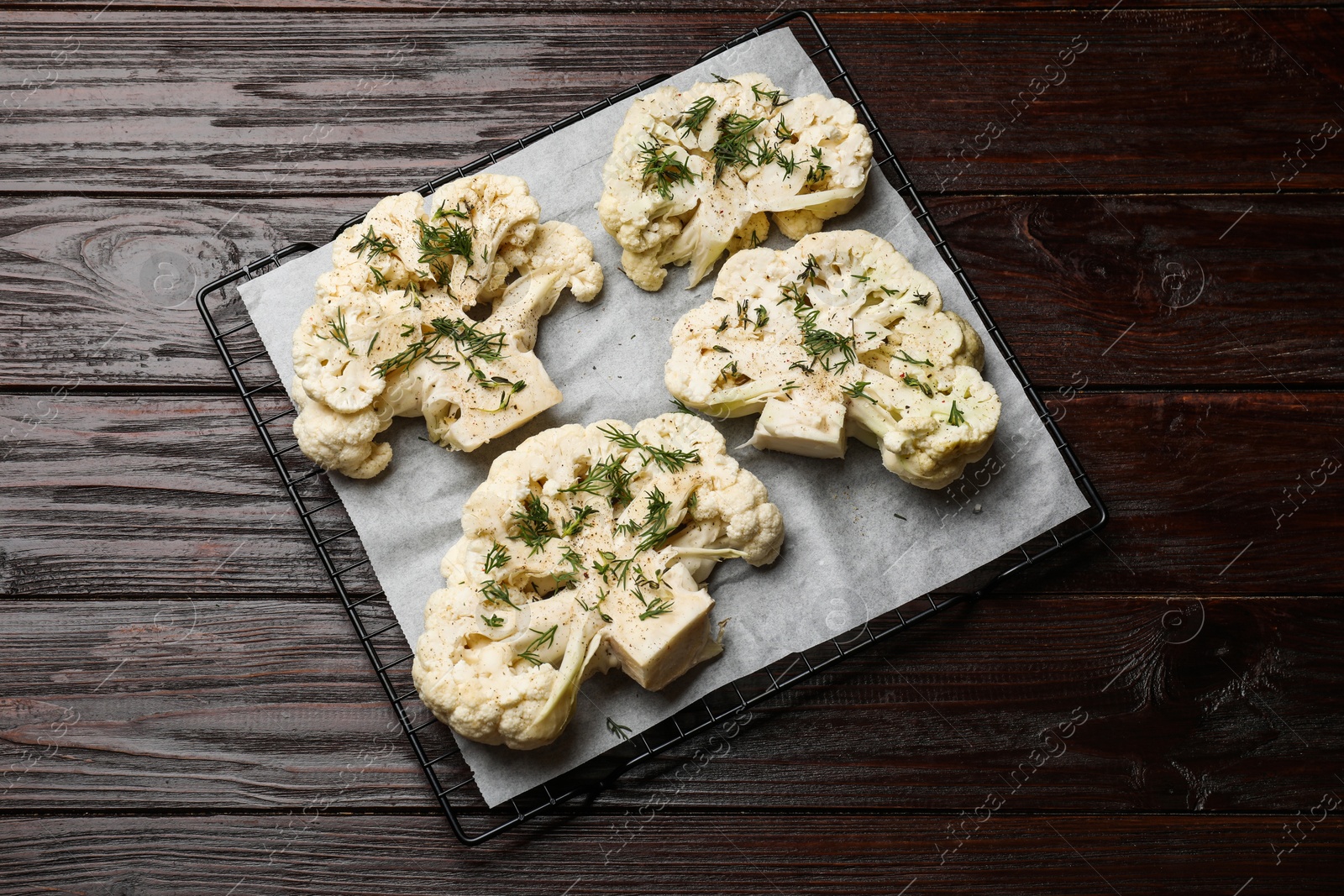 Photo of Uncooked cauliflower steaks and dill on wooden table, top view