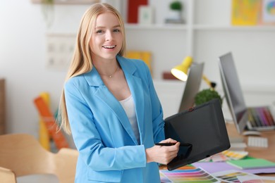 Beautiful young designer with tablet in office