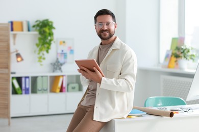 Photo of Smiling designer with tablet working in office