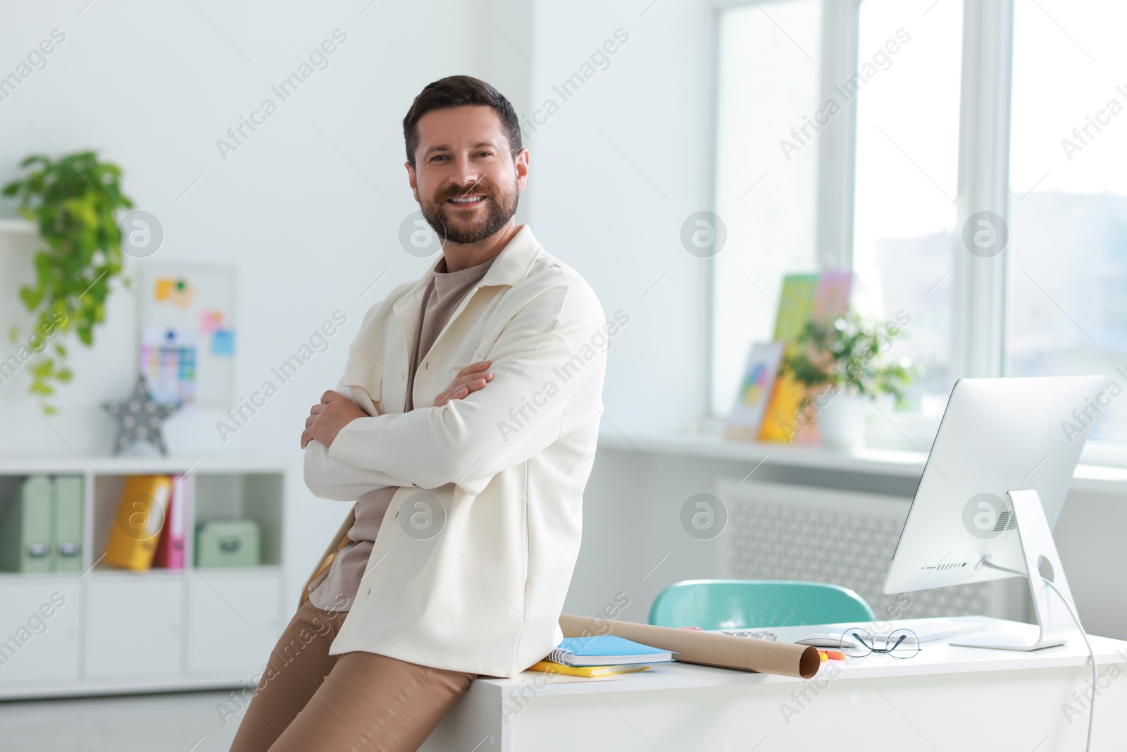 Photo of Portrait of smiling designer near table in office