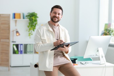 Smiling designer with tablet working in office