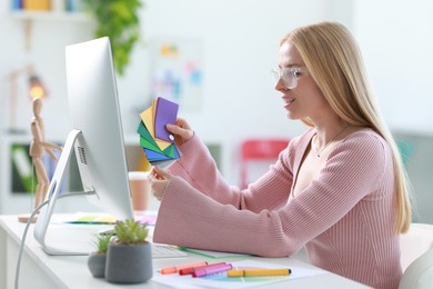 Designer with color samples working at table in office