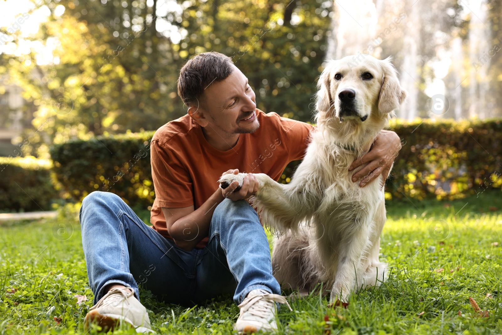 Photo of Smiling man with cute Golden Retriever dog on spring day