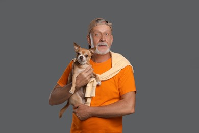 Portrait of handsome senior man with cute Chihuahua dog on grey background