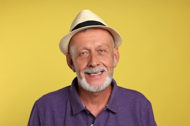 Portrait of happy senior man on yellow background