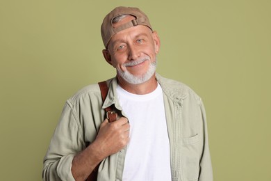 Portrait of handsome senior man with backpack on green background